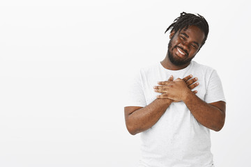 Portrait of pleased cute plump african-american guy with beard and moustache, tilting head and...