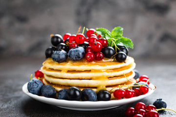 Pancakes with fresh berries. Pancakes with raspberry, blueberry, redcurrant, black currant and honey