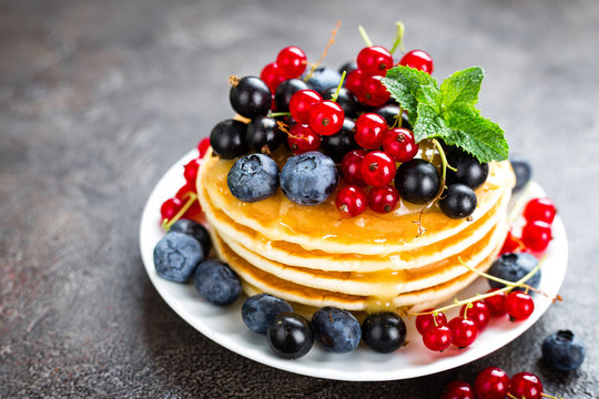 Pancakes with fresh berries. Pancakes with raspberry, blueberry, redcurrant, black currant and honey