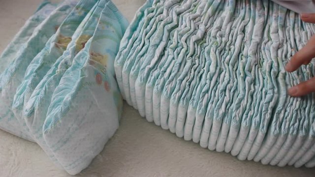 Girl is holding her hand in a pile with baby diapers, close-up