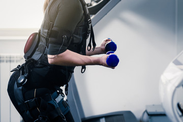 Closeup photo of woman in EMS suit exercising with dumbbells
