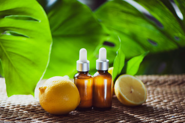 Bottles with lemon oil, fresh  fruit whole and half on a natural tropical background.