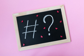 Blackboard with a chalk hashtag and a question mark written on it, with red hearts. Social media promotion concept.