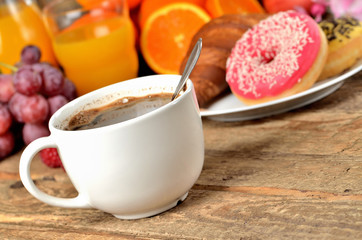 Cup of coffee, croissant, donuts, fresh fruit - grapes, orange and juice - breakfast