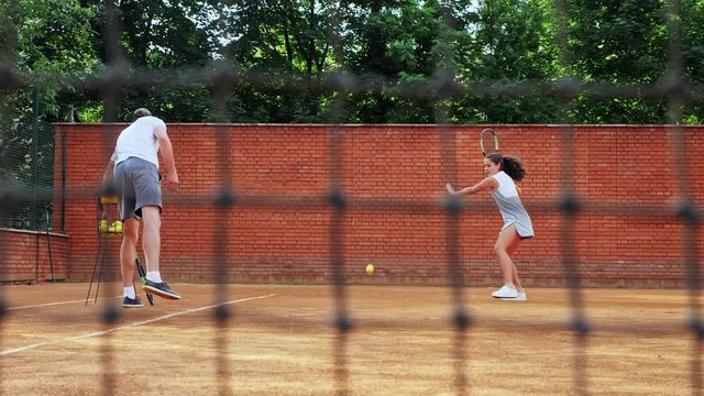 Coacher teaching young girl to playing tennis.