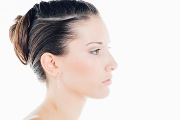 Profile of a young caucasian brunette poses for a beauty session in studio with white background