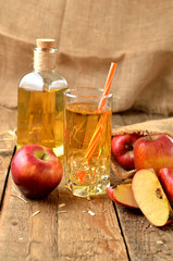 Homemade apple juice with ice, red apples, straw, still life on a wooden table vertical photo