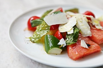 Delicious and healthy Raw Food: Cool, Refreshing Watermelon, cherry tomato, cucumber and parmesan cheese Salad. Topped with mint and drizzled with extra virgin olive oil. Natural light.