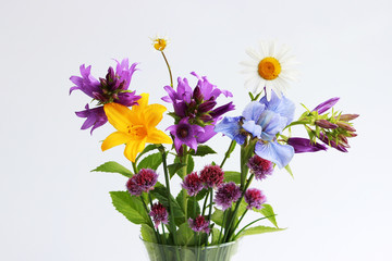 a bouquet of different wild field and garden flowers: chamomile, bell, lily, chives, iris.