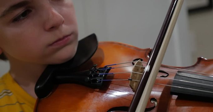 Close up of a young pre teenage boy concentrating and learning violin