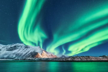 Fototapete Nordlichter Grüne Nordlichter auf den Lofoten, Norwegen. Nordlicht. Sternenhimmel mit Polarlichtern. Nachtwinterlandschaft mit Aurora, Meer mit Himmelreflexion und schneebedeckten Bergen. Natur. Reisen
