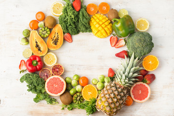 Fruits and vegetables rich in vitamin C in a frame, oranges mango grapefruit kiwi kale pepper pineapple lemon sprouts papaya broccoli, on wooden white table, top view, copy space, selective focus
