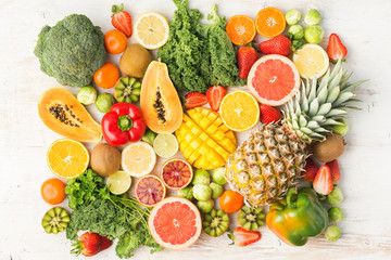 Fruits and vegetables rich in vitamin C arranged in rectangle, oranges mango grapefruit kiwi kale pepper pineapple lemon sprouts papaya broccoli, on white table, top view, selective focus