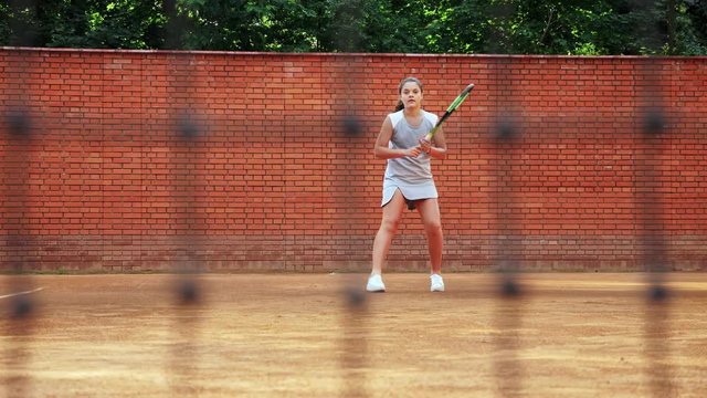 Young girl blocking the ball with the tennis rocket during the training