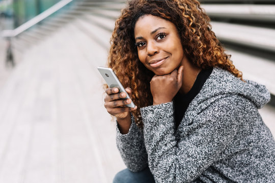 Smiling young black woman with mobile
