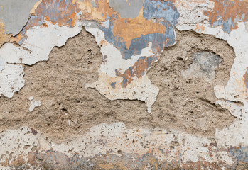 detail of old wall with crumbling plaster and peeling off paint