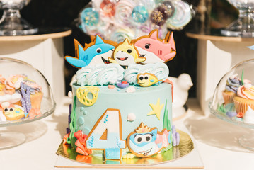 Fototapeta na wymiar Candy bar for your birthday. Children's party in the nature. Beautiful cake with fish, candy and number 4