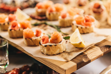Slices of smoked salmon with butter and white bread on a rustic wooden background. Rich buffet table
