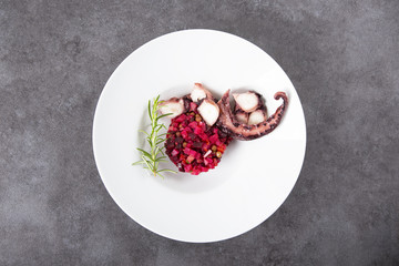 Salad from beets and octopus. Vinaigrette is a traditional Russian salad made from beets and vegetables. The background is gray. Top view. Copy space.
