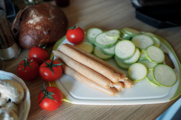 tomato, mushrooms, fresh zucchini, raw sausage lie on the table