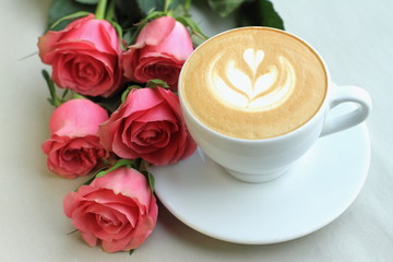 cappuccino in white cup with five roses on paper background