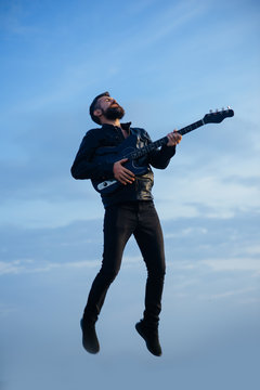 Music and freedom make him happy. Music, bearded hipster play guitar flying in blue sky