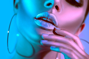 High fashion model woman in colorful bright neon lights posing in studio. Beautiful sexy girl, trendy glowing makeup, metallic silver lips - obrazy, fototapety, plakaty