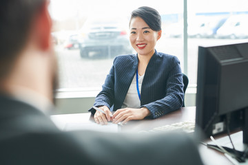 Asian smiling businesswoman sitting at the table together with client