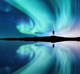 Foto op Plexiglas Noorderlicht en silhouet van staande man in de heuvel in Noorwegen. Aurora borealis en mens. Sterren en groene poollichten. Nachtlandschap met aurora, meer, hemelbezinning in water. Reis. Concept © den-belitsky