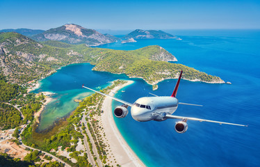Airplane is flying over islands and sea at sunrise in summer. Landscape with white passenger...