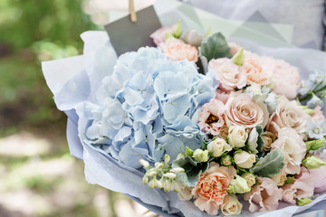 Beautiful summer bouquet. Arrangement with mix flowers. Young girl holding a flower arrangement with hydrangea. The concept of a flower shop. Content for the catalog