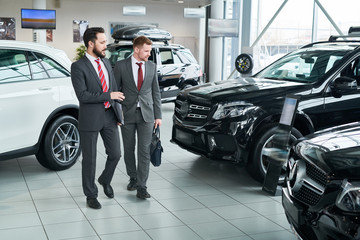 Salesman giving an advice to the man about new car at salon