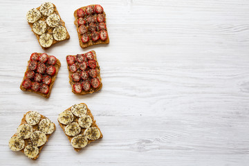 Vegetarian toasts with peanut butter, fruits and chia seeds on a white wooden table, from above. Dieting concept. Copy space.