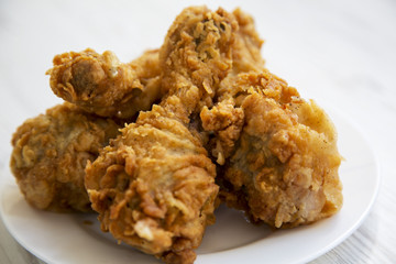 Fried chicken legs on a white plate, close-up.