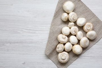 Top view, champignon mushrooms over white wooden background. From above, overhead. Copy space.
