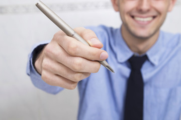 businessman smiling offering the pen to sign or hire