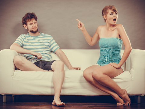 Man and woman having argument sitting on sofa at home