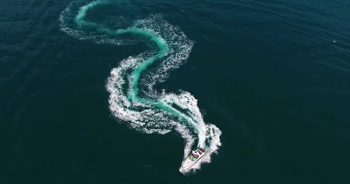 Top view fantastic figure of curve line in shape of dollar made with foamy speedboat traces on azure ocean water surface