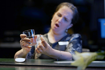 Woman drinks a pill from pain