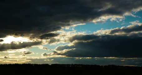 Timelaps of moving fluffy clouds in the evening sky during sunset  in  meadow