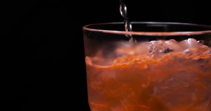 Orange alcohol cocktail in a glass, black background, strawberry, lime, black background, cold drink, ice, fresh.