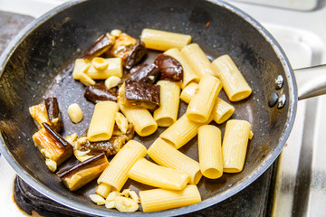 Cooking pasta (Rigatoni) with eggplant and tomato sauce in the restaurant kitchen.