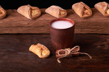 Cookies with cottage cheese and milk on wooden table background. Mini pies in desk. Rustic style.