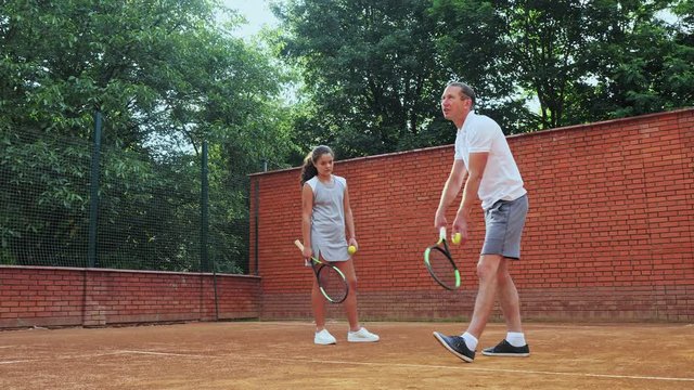 Coacher showing to the girl how to serve the ball