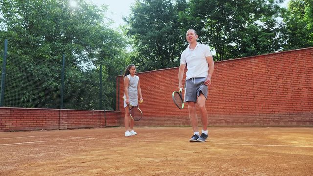 Coacher showing to the girl how to serve the ball