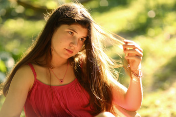 teenager girl with long brown damaged hair close up photo on summer garden background with back sun...