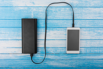 Modern White Smart Phone With Drained Battery Connected To Big External Power Bank Battery Charging...