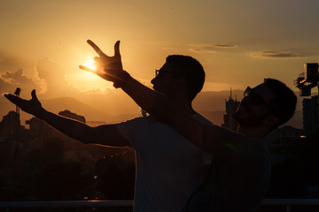 TWO BEST FRIENDS FOOLING AROUND ON BALCONY ON SUNSET