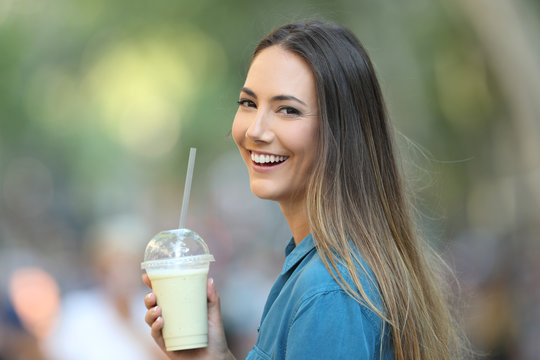 Happy lady holding a smoothie looking at camera