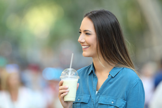 Happy woman holding a smoothie looking at side